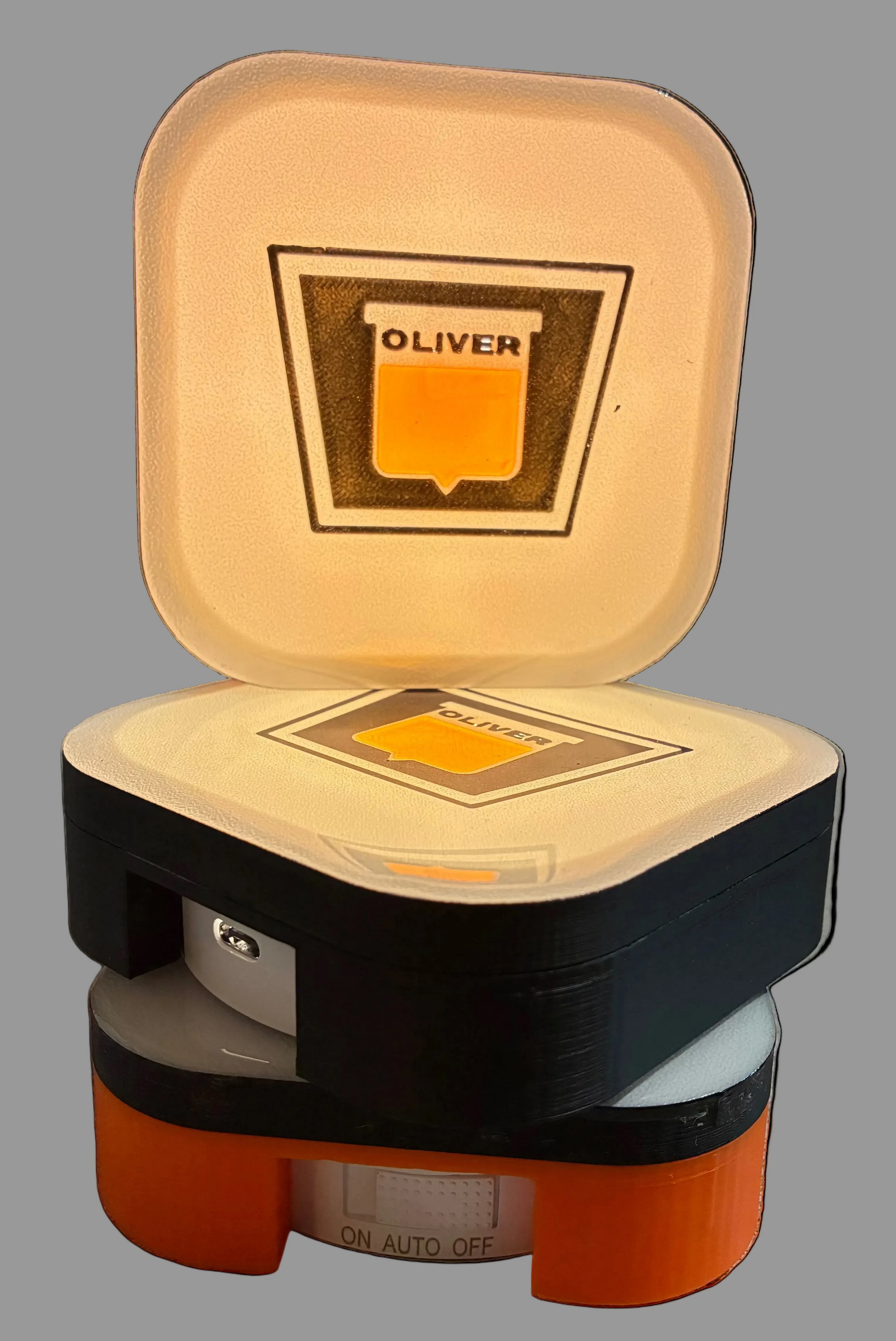 Small, square-shaped light with 'OLIVER' branding on a gray surface.